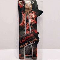 Front view of chopsticks in new packaging shaped like Freddy's glove with horror graphic and text.