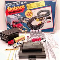 Photo of the slot car set components laid out with original box showing track layout and contents list.