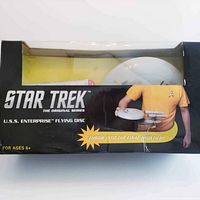 Photograph of the front side of the black box packaging depicting the flying disc toy and Star Trek branding.