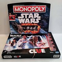 Photo shows two board games: Monopoly Star Wars edition with space-themed box art, and Star Wars Clue edition featuring classic character art from the Star Wars saga. Both boxes display branding from Hasbro and Disney and are in good shape.