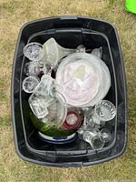 Top view of multiple assorted crystal and glass items including bowls, plates, platters, and stemware contained in a black plastic bin.