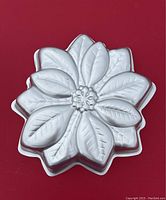 Metal poinsettia flower shaped cake pan with detailed leaf and petal textures.
