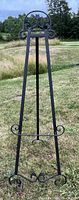 Full view of metal art easel standing on grassy lawn outdoors