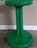 Green plastic wobbly fidget stool showing round base, single column support, and round seat top.
