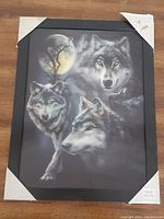 Framed hologram wall art depicting three wolves with moon and tree background; packaging corners intact.
