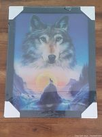 Photo of the hologram wall art depicting a wolf face and howling wolf scene, showing the frame with protective corner covers still on.