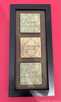 Framed wall sign with three ceramic or stone plaques with inspirational phrases.