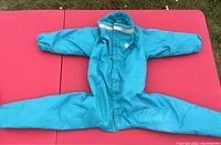 Full view of teal blue dog rain and snow suit laid flat showing front zipper and full coverage design.
