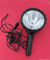MotoMaster emergency spot light featuring large reflector, black handle, and car adapter cord.