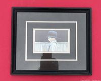 Framed artwork showing an Amish boy in an oversized hat with black frame and double matting