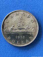 Reverse of 1953 Canadian silver dollar displaying canoe scene, year, and inscriptions on the coin edge.
