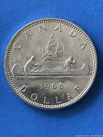 Obverse side of the 1966 Canadian silver dollar coin showing two people paddling a canoe, trees, 'CANADA', year '1966', and 'DOLLAR' inscription.