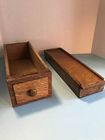 Two wooden boxes, one with sliding lid and one open-top with drawer, shown side by side