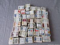 Bundles of Canadian postage stamps arranged on a surface, each bundle labelled by hand with years and catalogue numbers, showing stamp fronts with varied colors and designs
