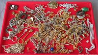 Overhead photo showing a large assortment of mixed metal chains, clasps, pendants, and jewelry findings arranged on a red background.