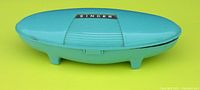 Turquoise rounded Singer storage box closed showing top with silver Singer label.