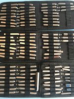 Three black cases containing sets of metal punch stamps with alphabet letters arranged neatly in slots.