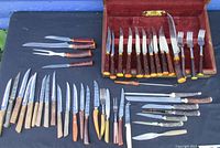 Overview of all steak carving knives, forks, and utensils spread out alongside the wooden display box.