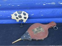 Bellows and pig-shaped hook on black surface with blue wooden background