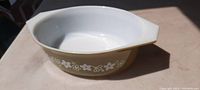 Top angle view of Pyrex oval serving dish showing white interior and olive green exterior decorated with white flowers