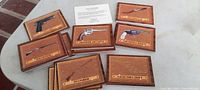 Photo showing multiple recognition cards depicting various firearms, arranged on a surface with two original boxes and a small informational card.