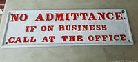 Full rectangular cast iron sign with embossed red lettering on white background.
