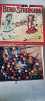 Open box showing contents including wooden beads of various colors and string cords