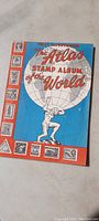 Front cover of the Atlas Stamp Album depicting the title and artwork.