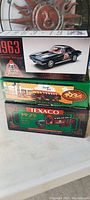 Three boxed die cast vehicles including 1963 Corvette and Texaco trucks stacked