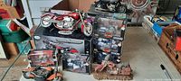 Collection of die-cast toy motorcycles including a red chopper on box, and multiple boxed motorcycles stacked in background