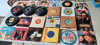 Wide overview of table covered with stacks of 7-inch singles in picture and paper sleeves, assorted artists.