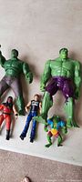 Large Hulk figures and smaller superhero and character figures on a light surface
