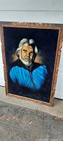 Full view of the vintage painted Kenny Rogers portrait on velvet with solid wood carved frame.