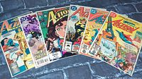 Eight DC Action Comics comic books laid out showing a variety of covers featuring Superman and other characters in colorful illustrated comic style.