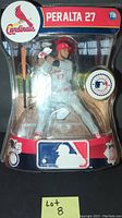Front view of the first Johnny Peralta #27 Imports Dragon figure in original packaging, showing batting pose and included bat accessory.