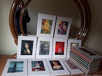 Photo showing front covers of 11 art books propped on a table, each in a white protective sleeve featuring various famous artworks by major artists.