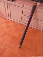 Full length view of the telescope standing upright on a parquet floor, showing leather bound tube and brass tip.