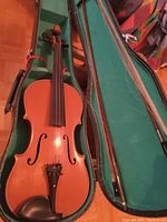 Violin and two bows inside a green lined case, violin body in very good condition.