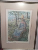 Full view of the framed lithograph showing a woman seated outdoors in a pastoral scene.