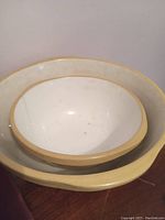 Top view of set of 2 vintage Green's England pottery bowls, showing cream interior and yellow rim.