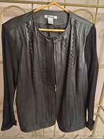 Front side of black ladies sweater/light coat showing faux leather front panels with stitched pattern, round neck, and zipper closure.