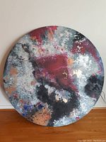 Front view of large circular abstract artwork by Mia Archer with vibrant colors and metallic highlights.