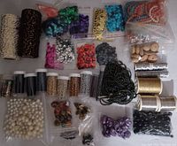 Photo displaying small bags of assorted seed beads, wooden beads, metallic threads, and pearl beads