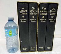 Set of four folio society slipcased books by Barbara W. Tuchman with a water bottle for size reference.