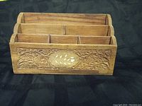 Front view of carved wooden desk organizer showing decorative inlay and compartment divisions.