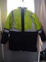 Front view of large tall utility jacket showing bright yellow upper half, black bottom half, reflective strips on chest, sleeves, and waist