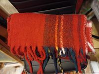 Photo of the folded red and plaid acrylic winter scarf showing the fringed ends with curled tassels.
