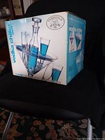 Box displaying the vodka chiller set brand Essentials Bar Artifacts with an image of the glassware and metal holder