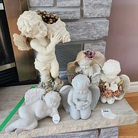 Group photo of all five angel statues on a stone surface in an indoor setting.