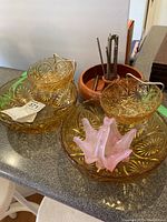 Three amber glass chip and dip bowls, pink glass candy dish displayed with wooden bowl and nut cracking tools